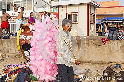 A portrait of a poor young Hard working man selling cotton candy taffy to tourists. Editorial Stock Photo