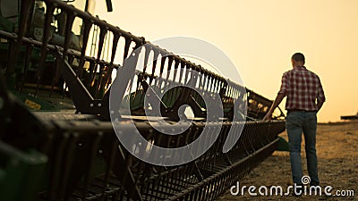 Rancher check field thresher reel farming vehicle at golden sunset countryside. Stock Photo