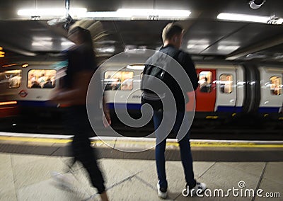 Random passenger people at the underground tube station with moving train motion blurred. London England Stock Photo