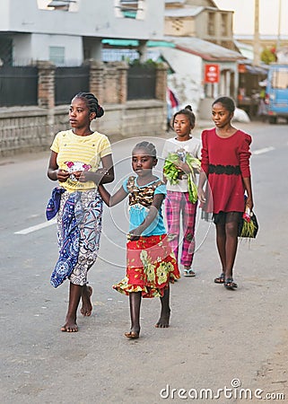 Ranohira, Madagascar - April 29, 2019: Group of four unknown young Malagasy girls wearing bright coloured clothes walking barefoot Editorial Stock Photo