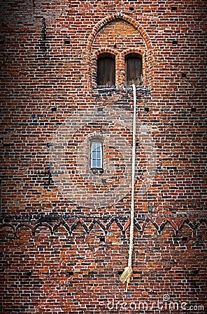 Rapunzel story, a long blond hair plait hanging out of the window of an old brick tower Stock Photo