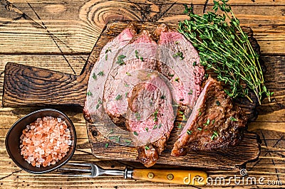 Rare slices of Roast beef sirloin tri tip steak bbq on a wooden cutting board. wooden background. Top view Stock Photo