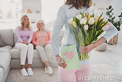 Rare view photo of little girl keeping postcard tulips bunch hiding behind back to congratulate mother granny Stock Photo