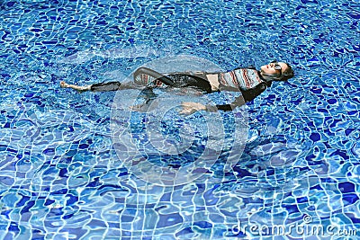 Rash guard swimming suit protect skin from uv sun ray, Woman floating in clear blue swimming pool. Stock Photo