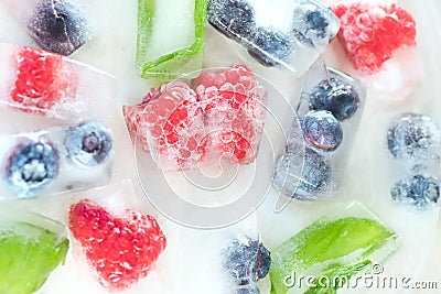 Raspberries, blueberries and mint leaves in ice cubes Stock Photo