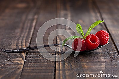 Raspberries on old spoon and mint on grunge wooden board Stock Photo