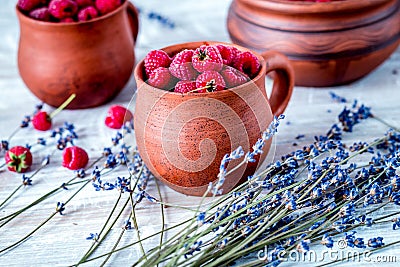 raspberry in pottery and lavender flowers on rustic background Stock Photo