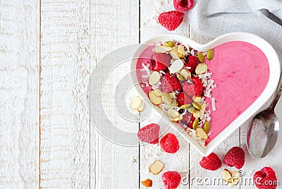 Raspberry smoothie in a heart bowl with superfoods, side border Stock Photo