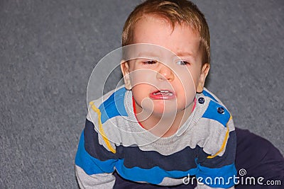 A rasped and hurt child sits on the floor. The little boy pouted Stock Photo