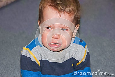 A rasped and hurt child sits on the floor. The little boy pouted Stock Photo