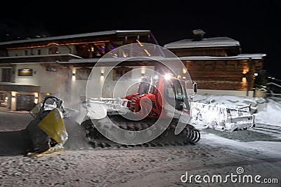 Ratrack snow grooming machine preparing slopes for skiers on ski resort in mountains on night Stock Photo