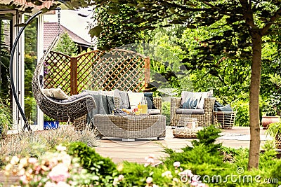 Rattan garden furniture and hanging chair on wooden terrace of h Stock Photo