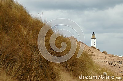 Lighthouse behind sand dunes Stock Photo