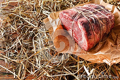 Raw aged prime black angus beef in craft papper on straw Stock Photo