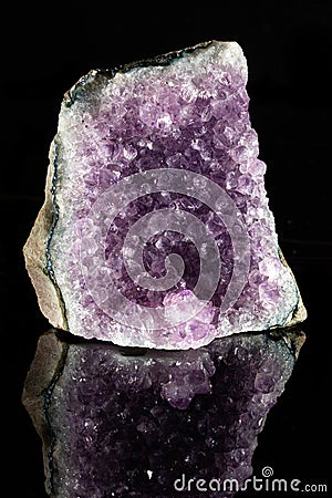 Raw amethyst stone on a black reflective background. Stock Photo