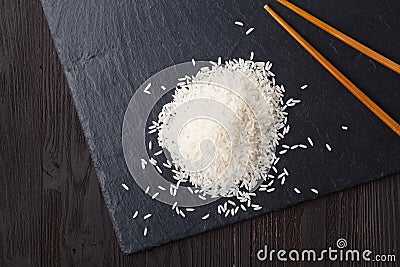 The raw basmati rice is scattered on a black slate. place for text Stock Photo