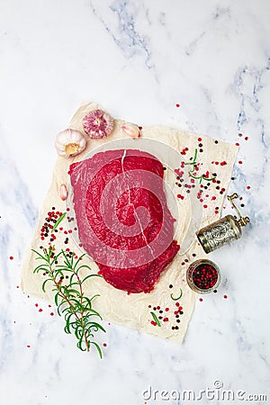 Raw beef. Fresh organic meat and spices on the marble table. Salt, pepper, garlic, rosemary and olive oil. We prepare a delicious Stock Photo