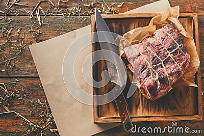 Raw aged prime black angus beef in craft papper on rustic wood Stock Photo