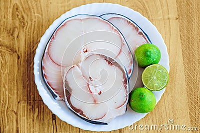 Raw blue shark meat and limes on white plate Stock Photo