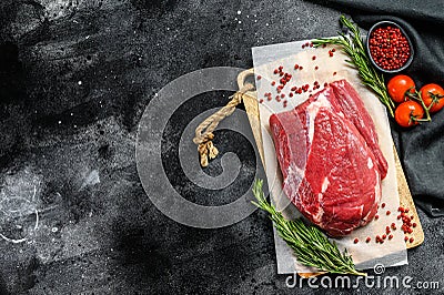 Raw brisket beef cut on a wooden cutting board. Black Angus beef. Black background. Top view. Copy space Stock Photo