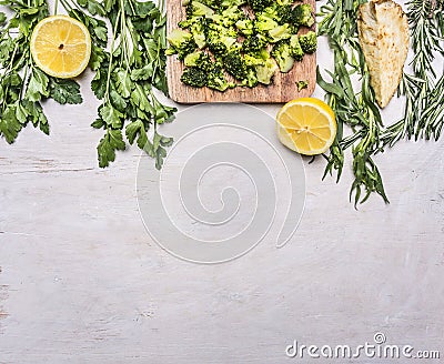 Raw broccoli in a cutting board with herbs, lemon, celery root border ,place for text wooden rustic background top view close Stock Photo