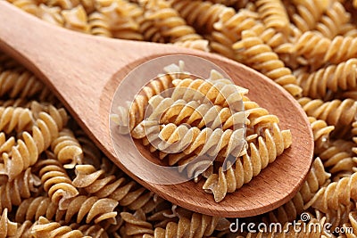 Raw brown pasta on a wooden spoon Stock Photo