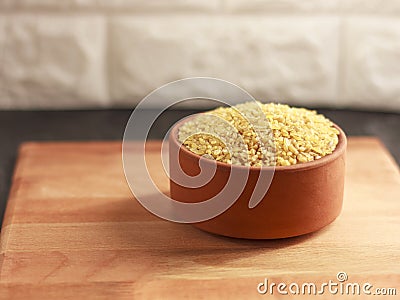 Raw bulgur in a clay bowl on a wooden board Stock Photo