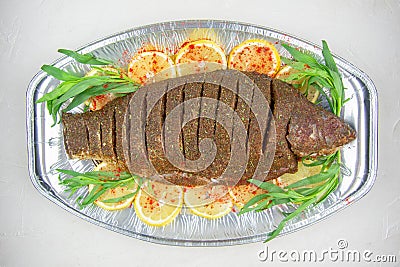 Raw carp in spices, prepared for baking. On a pillow of lemons and herbs. Stock Photo