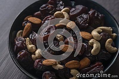 Raw cashew nuts and figs served in black bowl . Stock Photo