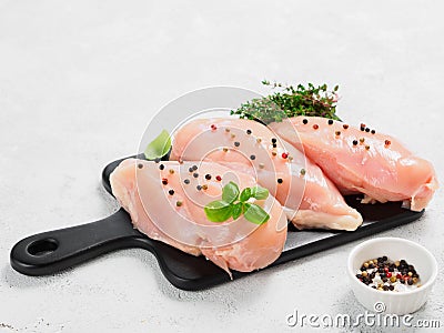 Raw chicken breast with fresh basil on black cuttingboard Stock Photo