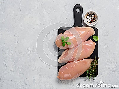 Raw chicken breast with fresh basil and thyme on black cuttingboard Stock Photo