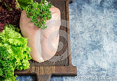 Raw chicken breast, vegetables and green salad on chopping board. Stock Photo