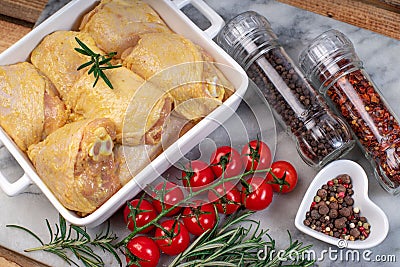 Raw chicken legs in baking dish .Raw chicken legs in a baking dish with tomatoes and spices on a cutting board Stock Photo