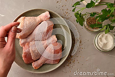Raw chicken in a plate. Marinated meat, with oregano, herbs and paprika. Raw chicken legs, step by step cooking. Top view, gray Stock Photo