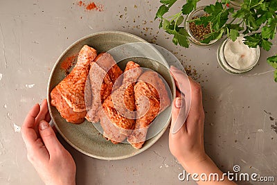 Raw chicken in a plate. Marinated meat, with oregano, herbs and paprika. Raw chicken legs, step by step cooking. Top view, gray Stock Photo