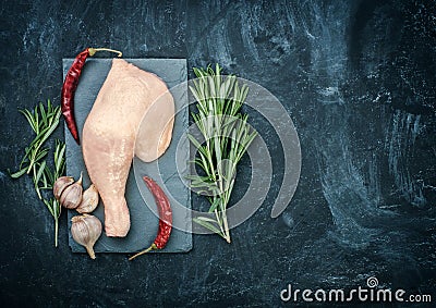 Raw chicken thigh on black stone plate. Stock Photo