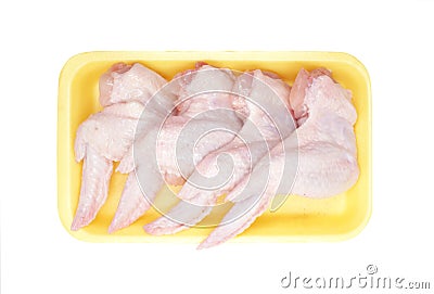 Raw Chicken wings in a yellow polystyrene container isolated on white background. Four fresh chicken parts for cooking. Top view. Stock Photo