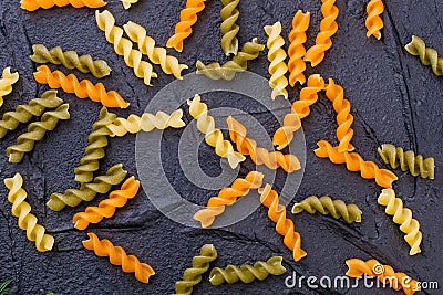 Raw colored spiral pasta on slate. Stock Photo