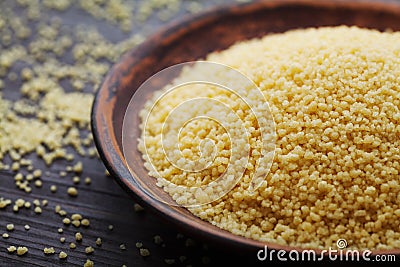 Raw couscous in bowl on dark wooden table Stock Photo