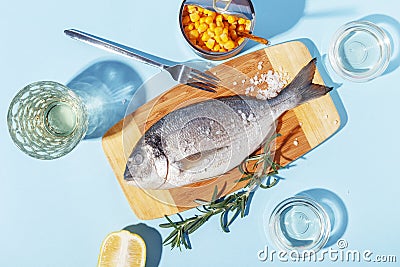 Raw dorado fish on a wooden board, ingredients for cooking and spices on a blue background Stock Photo