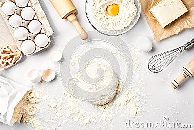 Raw dough ready for kneading on white table. Bakery ingredients, eggs, flour, butter. Shapes for making cookies. Stock Photo
