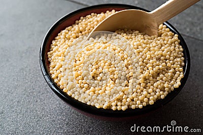 Raw Dry Organic Couscous in a Bowl with Wooden Spoon / Turkish Kuskus. Stock Photo