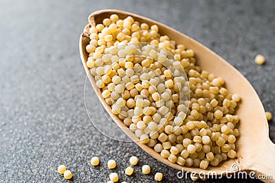 Raw Dry Organic Couscous in Wooden Spoon / Turkish Kuskus Stock Photo