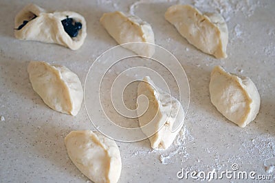 Raw dumplings with currants lie on a table sprinkled with flour. Stock Photo