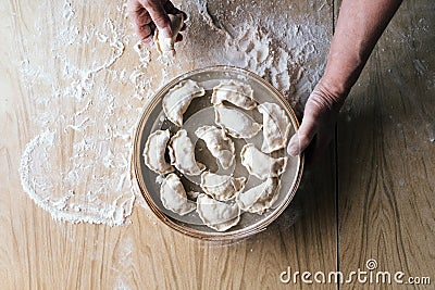 Raw dumplings, pierogi or pyrohy, varenyky, vareniki, served with cottage cheese lay in sieve Stock Photo