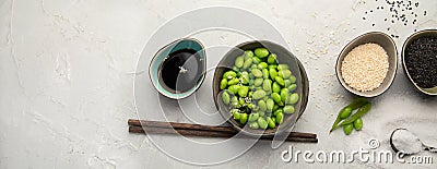 Raw edamame soya beans with salt and sauce on light gray background Stock Photo