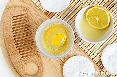 Raw egg in the small white bowl, wooden hair brush, lemon juice with lemon slice. Natural homemade hair treatment and zero waste Stock Photo