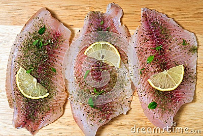 Raw fish fillet of tilapia on a cutting Board with lemon and spices Stock Photo