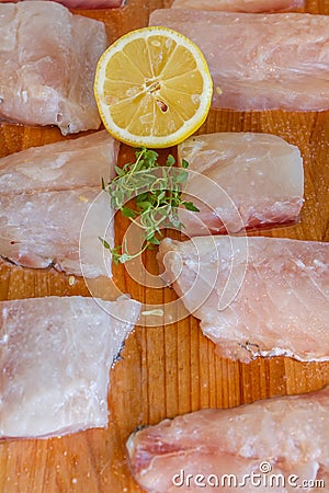 Raw fish slices with lemon on wooden cutting board Stock Photo
