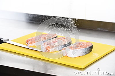 Raw fish steaks with spices on yellow cutting board. Stock Photo